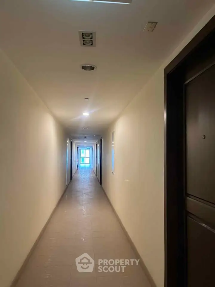 Long corridor in modern apartment building with bright lighting.
