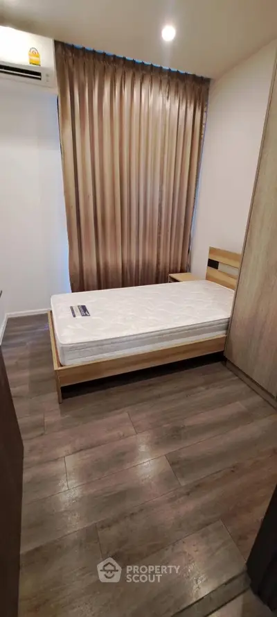Cozy bedroom with wooden flooring and modern air conditioning unit.