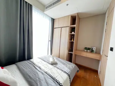 Modern bedroom with natural light, wooden flooring, and built-in wardrobe in a stylish apartment.