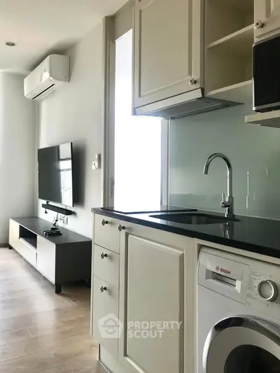 Modern kitchen with sleek appliances and cozy living area in a stylish apartment.