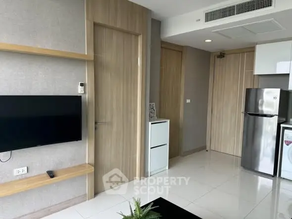 Modern apartment interior with sleek design, featuring a wall-mounted TV and stainless steel appliances.