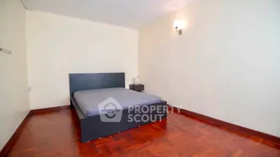 Spacious bedroom with wooden flooring and modern minimalist design.