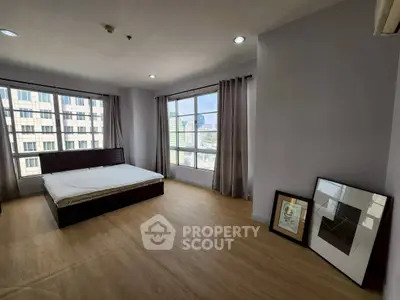 Spacious bedroom with large windows offering city views, featuring modern decor and natural light.