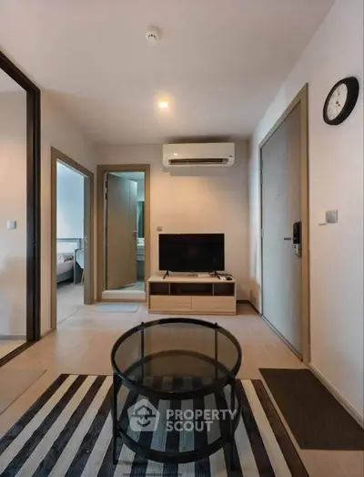 Modern living room with sleek furniture and stylish decor, featuring a TV and air conditioning unit.