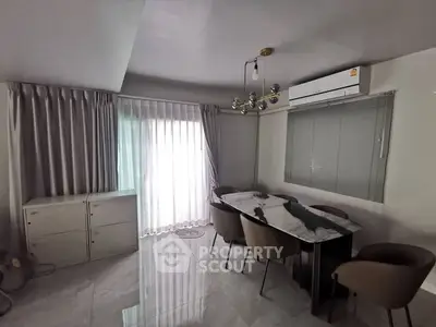 Modern dining area with sleek table and chairs, featuring elegant lighting and large window.