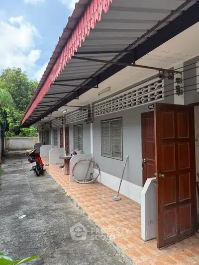 Charming single-story building with open corridor and red roof, ideal for residential or rental use.