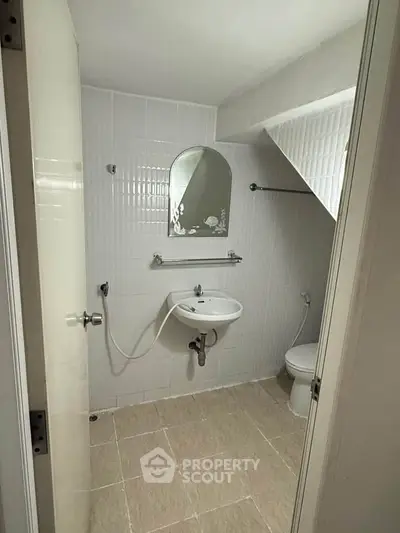 Compact bathroom with white tiles and modern fixtures in a cozy real estate property.