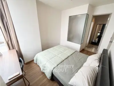 Modern bedroom with natural light, wooden flooring, and minimalist decor in a stylish apartment.