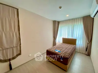 Cozy bedroom with natural light, featuring a comfortable bed and elegant curtains.