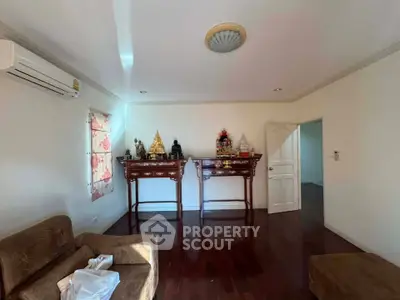 Spacious living room with wooden flooring and traditional decor, featuring air conditioning and ample natural light.