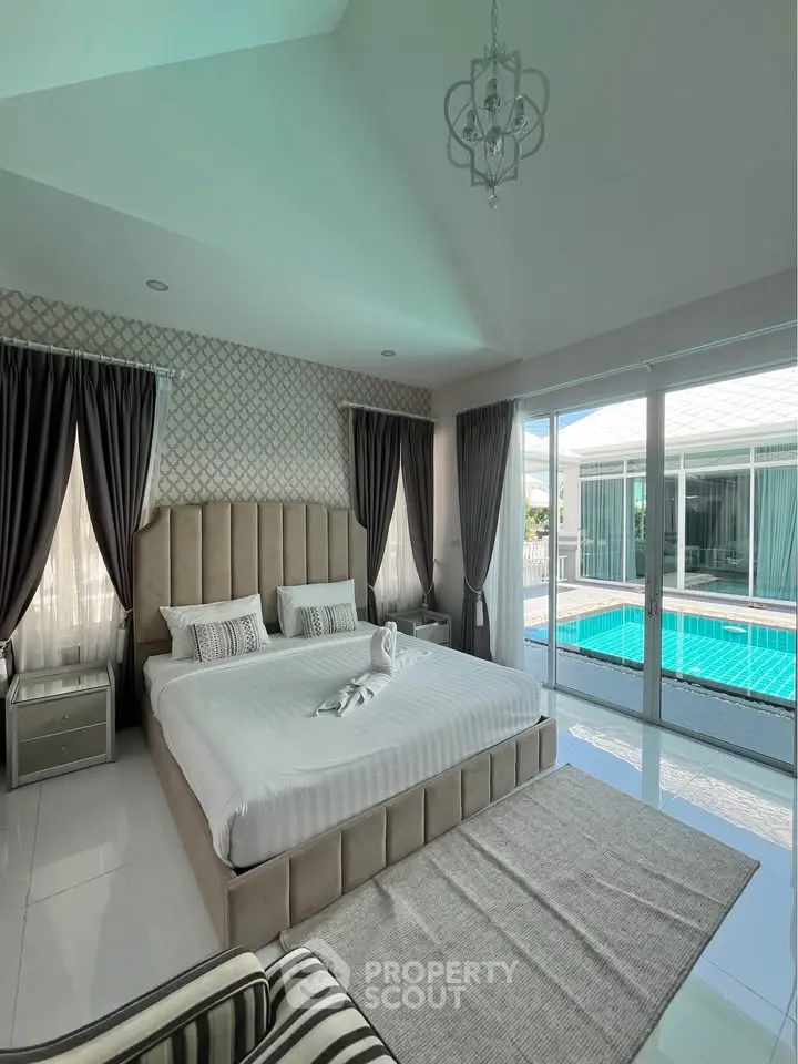 Luxurious bedroom with pool view, elegant decor, and ample natural light in a modern home.