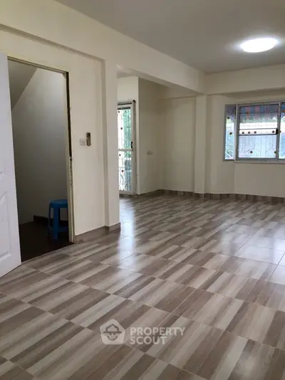 Spacious open-plan living area with tiled flooring and natural light.
