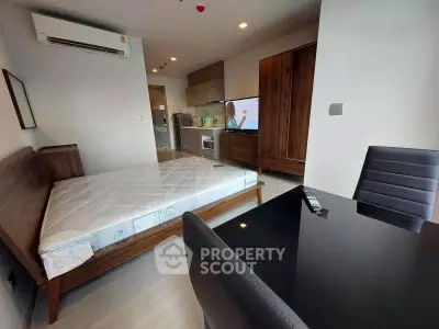 Modern studio apartment with sleek furniture and integrated kitchen appliances.
