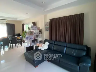 Spacious living room with black leather sofa and dining area, perfect for family gatherings.