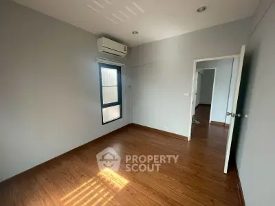 Spacious empty room with wooden flooring and air conditioning, perfect for customization.