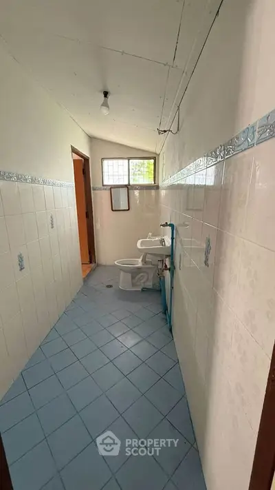 Narrow bathroom with blue tiled floor and basic fixtures.
