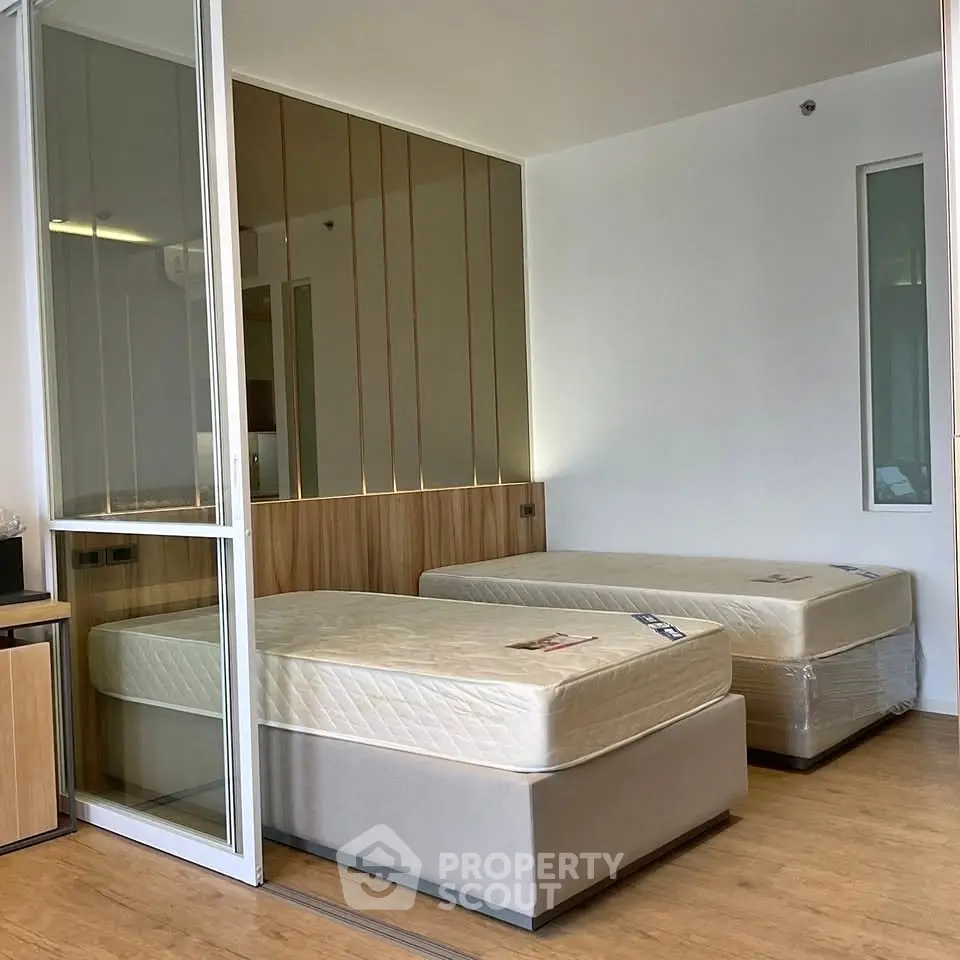 Modern bedroom with twin beds and sleek glass partition in stylish apartment.