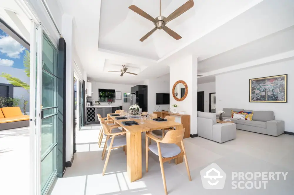 Spacious open-plan living area with high ceilings, modern furnishings, and seamless indoor-outdoor flow to a sunlit balcony, perfect for entertaining.