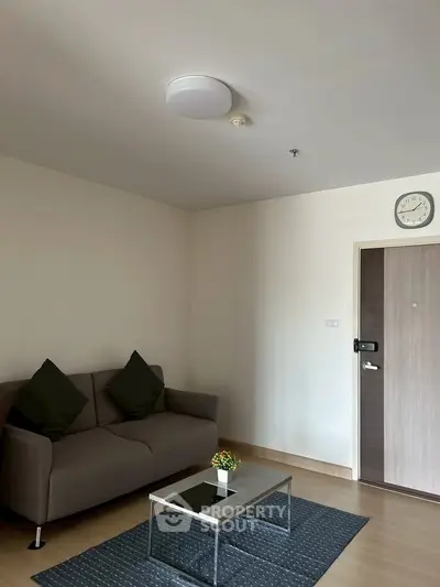 Modern living room with sleek sofa and glass coffee table in minimalist apartment.