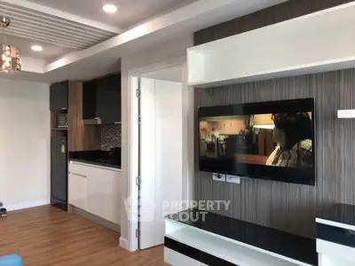 Modern living room with open kitchen and wall-mounted TV in stylish apartment.