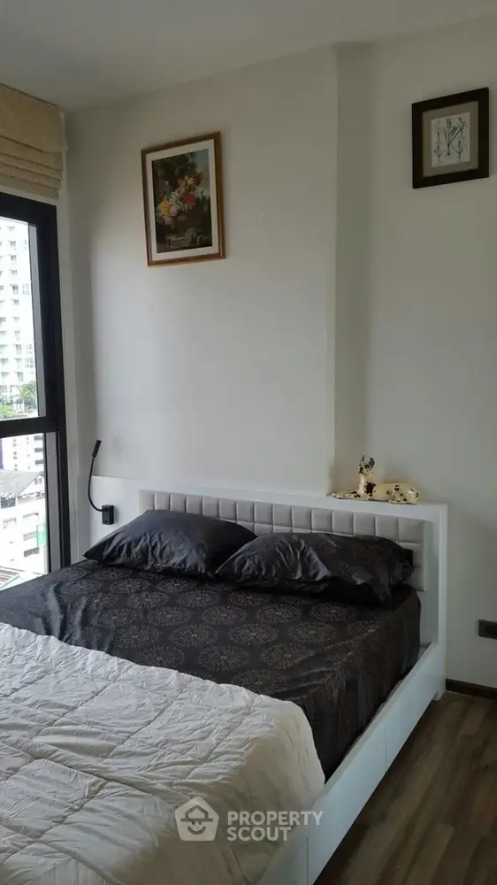 Modern bedroom with city view, stylish decor, and cozy ambiance in a high-rise apartment.