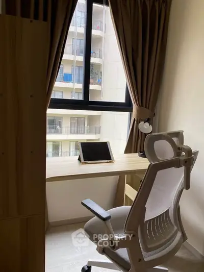 Cozy study nook with modern chair and tablet, overlooking urban balcony view.