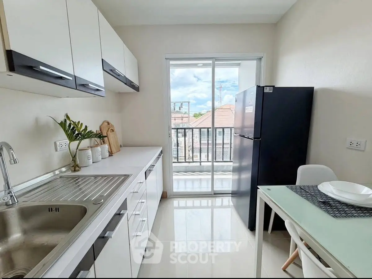 Modern kitchen with sleek cabinetry and balcony view, featuring a spacious fridge and dining area.