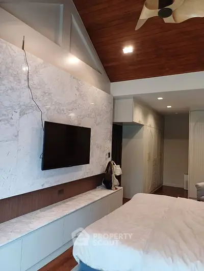 Luxurious bedroom with modern TV setup and stylish ceiling design