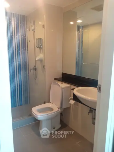 Modern bathroom with glass shower and sleek fixtures in contemporary apartment.
