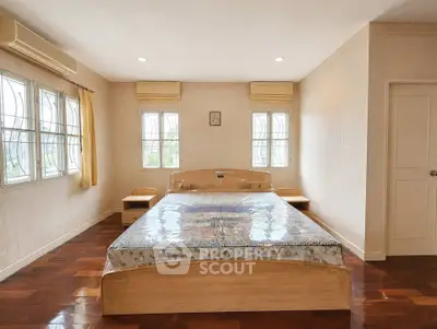Spacious bedroom with large windows and wooden flooring in a modern home.