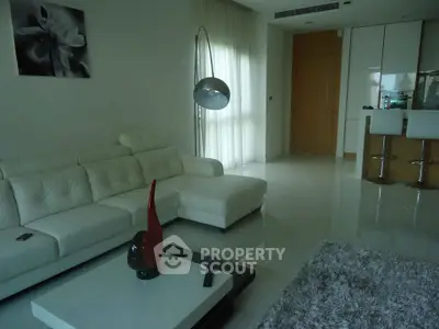 Modern living room with white leather sofa, stylish floor lamp, and sleek kitchen area.