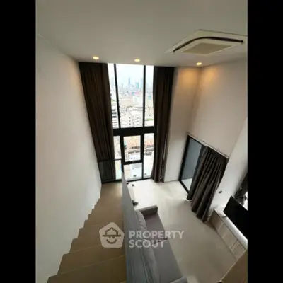 Modern loft-style living room with high ceilings and city view