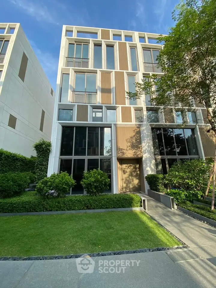 Modern multi-story building with sleek design and lush greenery in urban setting.
