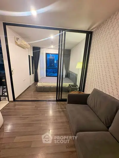 Modern apartment with glass-walled bedroom and cozy living area, featuring stylish decor and city view.