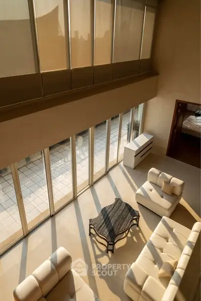Luxurious living room with high ceilings and large windows opening to a spacious balcony.