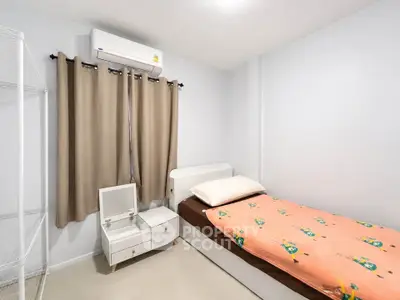 Cozy minimalist bedroom with single bed and air conditioning, perfect for a peaceful retreat.