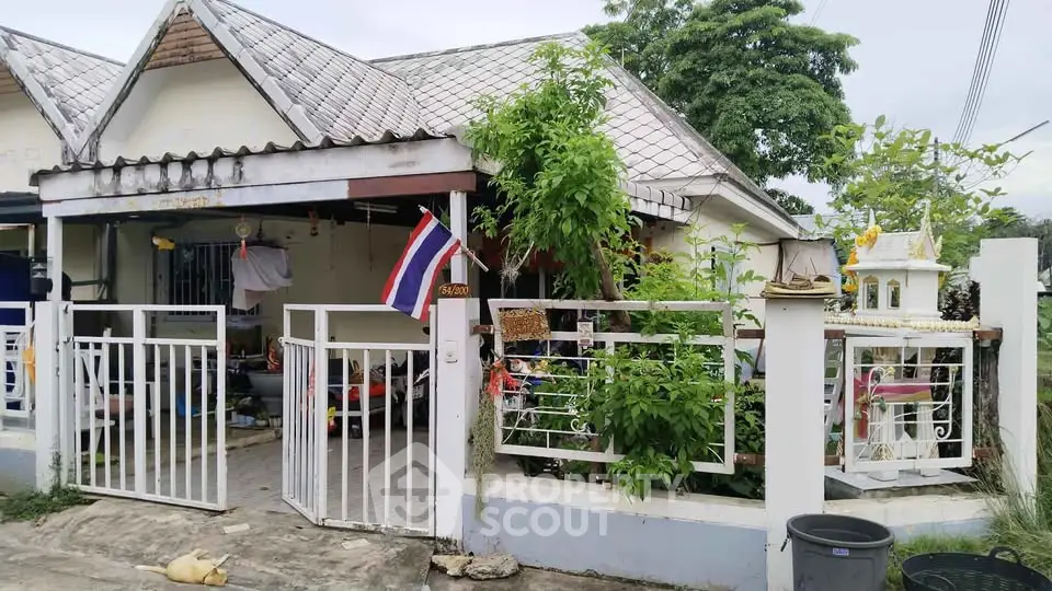 Charming single-story house with gated entrance and lush greenery