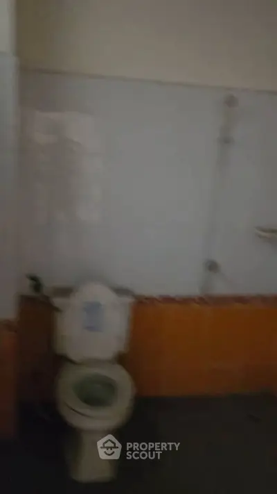 Basic bathroom with toilet and shower in need of renovation.