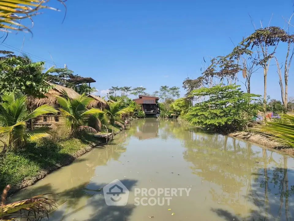 Scenic view of a serene waterfront property surrounded by lush greenery and clear blue skies.