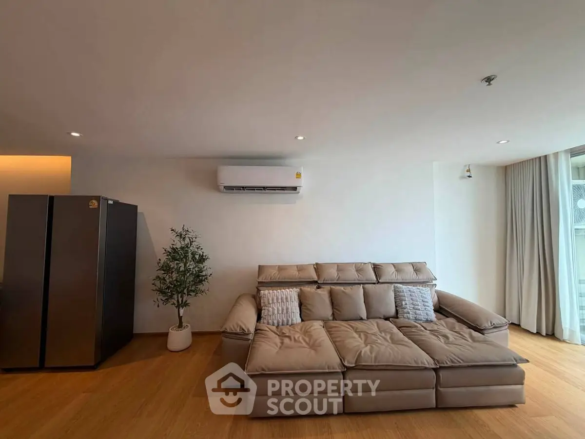Spacious living room with modern sofa and air conditioning, perfect for relaxation.