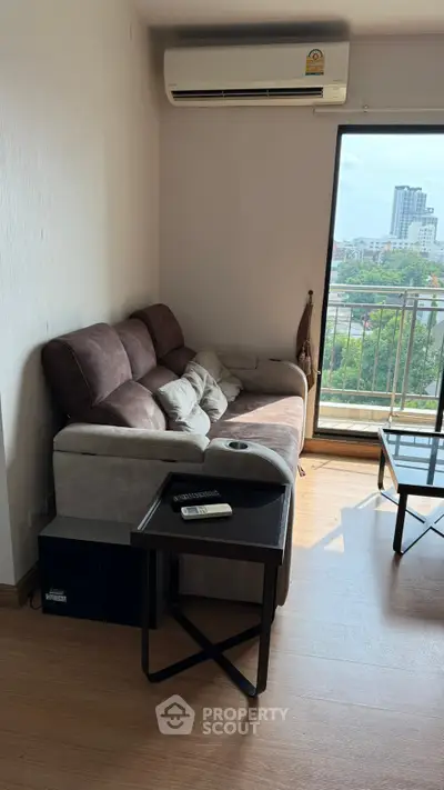 Cozy living room with modern sofa and city view balcony in urban apartment.