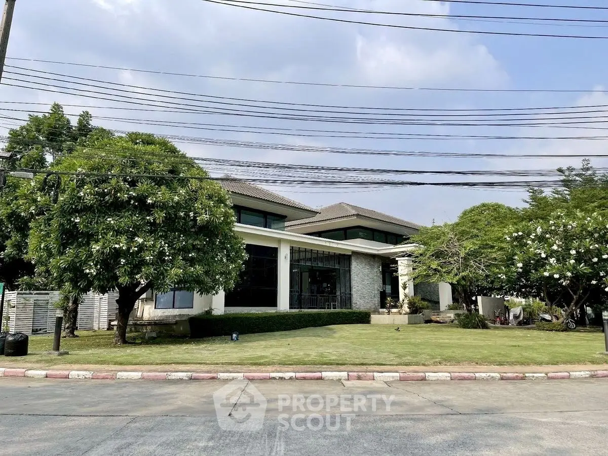 Luxurious modern house with lush garden and spacious lawn in a serene neighborhood.