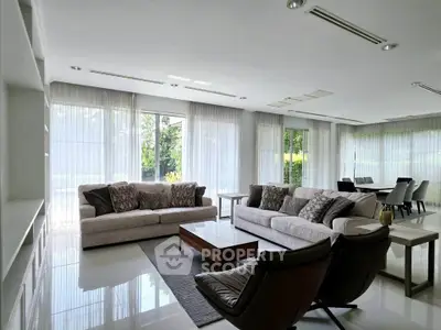 Spacious modern living room with elegant furniture and large windows offering natural light.