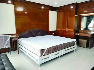 Spacious bedroom with elegant wooden furnishings and large bed in modern apartment.