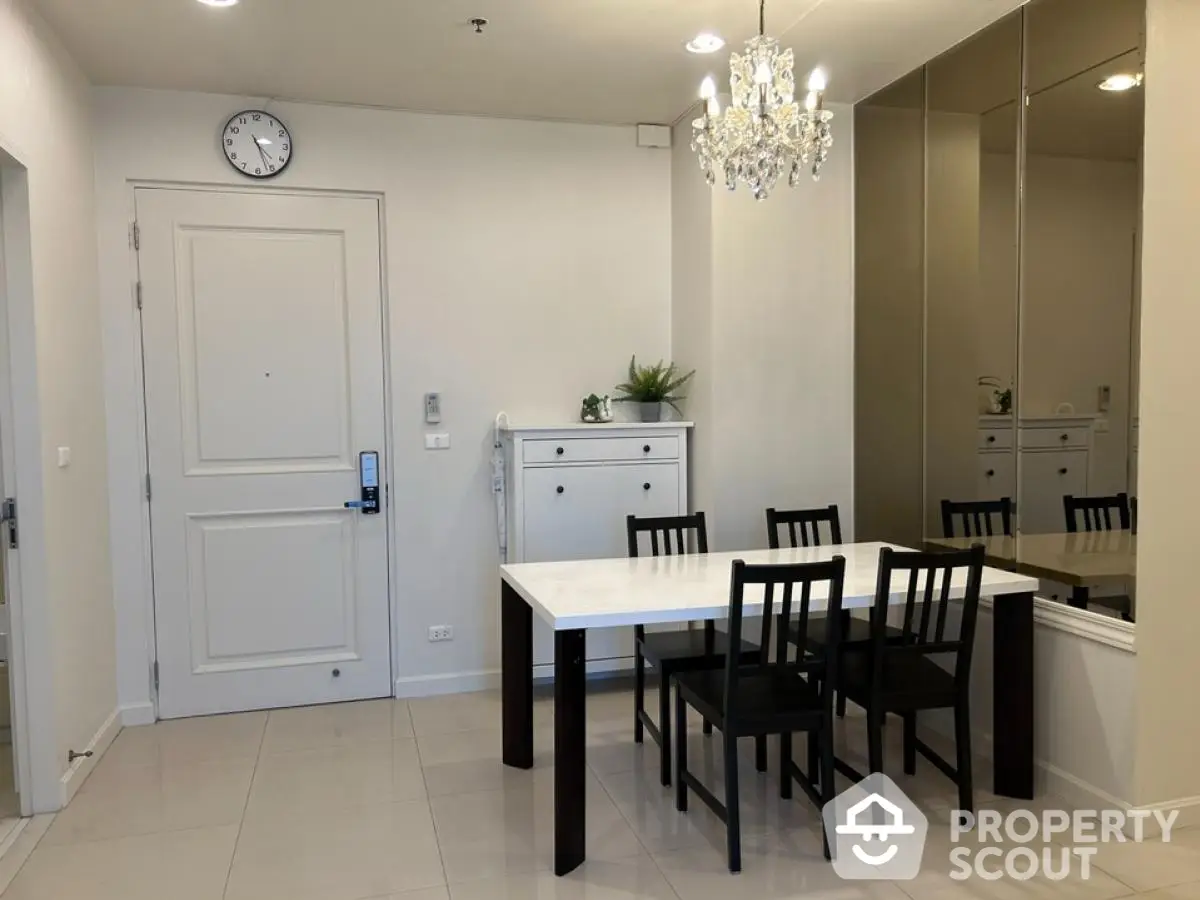 Elegant dining area with modern chandelier and sleek white table in a stylish apartment.