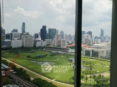 Stunning cityscape view from high-rise window overlooking lush green golf course and skyline.