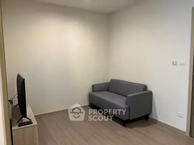 Minimalist living room with gray sofa and wall-mounted TV, perfect for cozy relaxation.