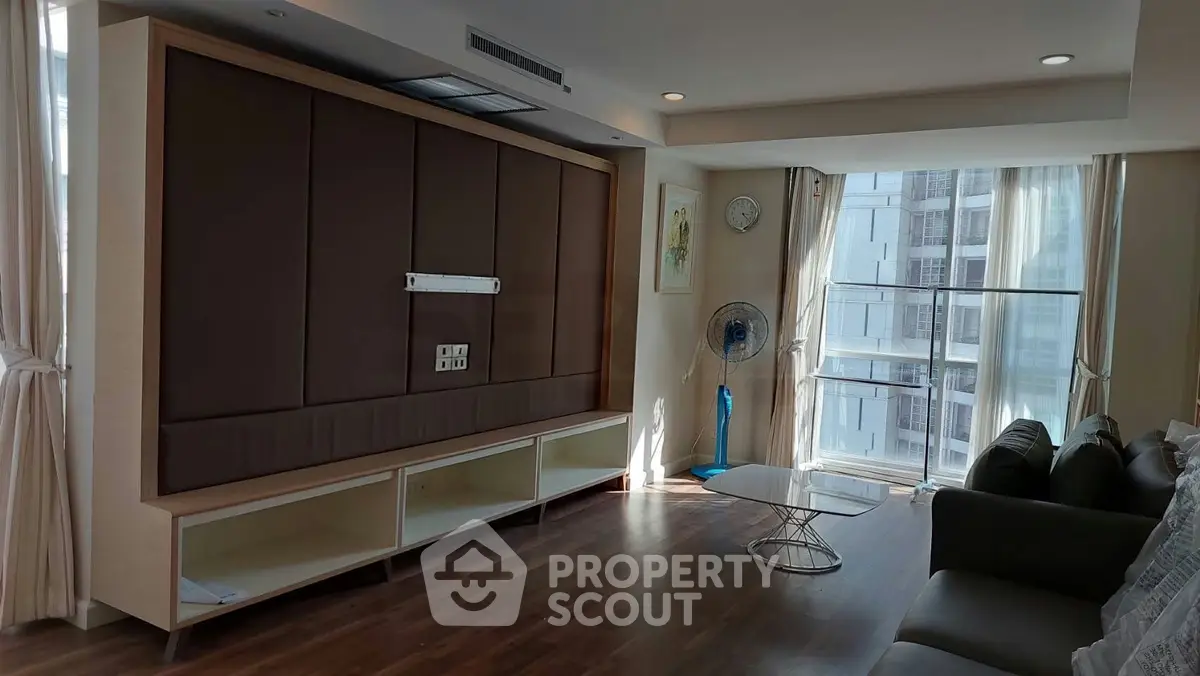 Spacious modern living room with large windows and stylish furniture in a high-rise apartment.