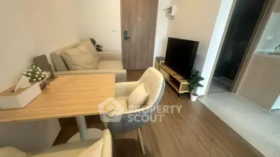 Cozy living room with modern furniture and TV, adjacent to a stylish kitchen.