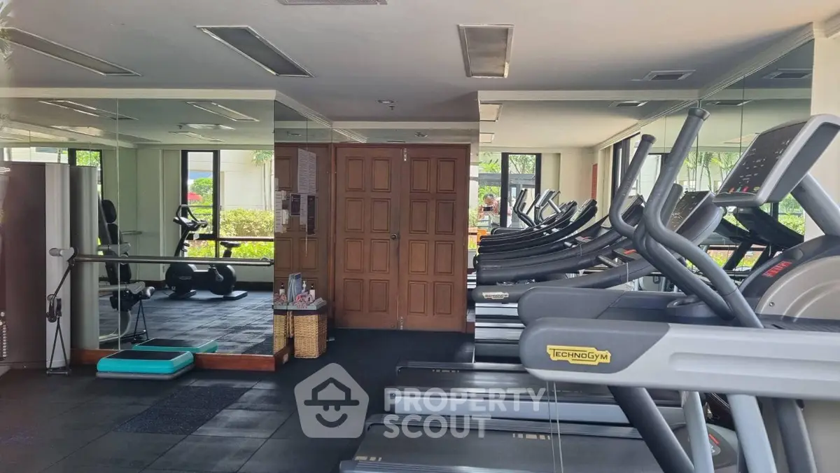 Spacious gym with modern equipment and mirrored walls in a luxury property.